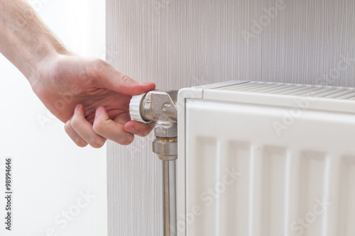 Radiator adjustment closeup. Man's hand adjusting radiator temperature.