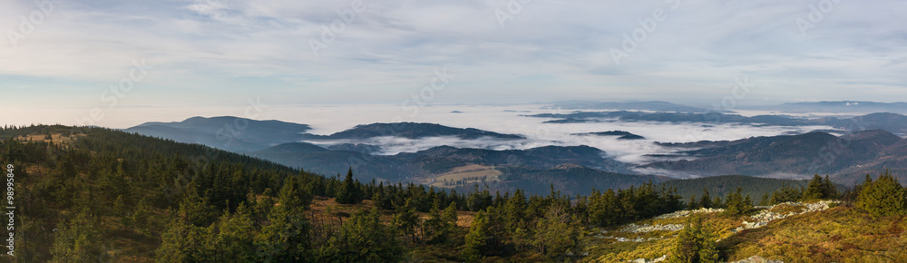 View from the autumn mountains into the valley with low clouds