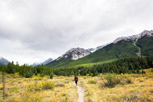 girl walking on a hiking trail going to the forest and mountains of alberta canada