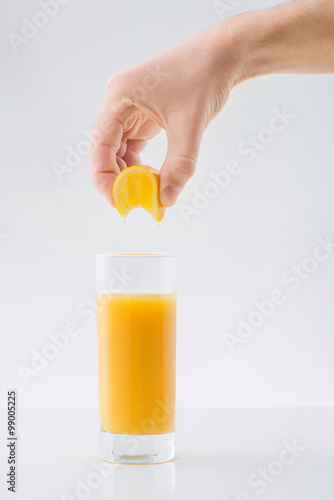 Human hand squeezing orange juice into the glass. photo