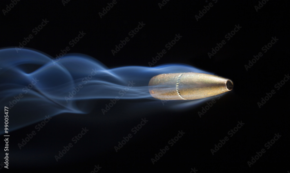One shot from a gun flying fast across a black background with a smoke contrail behind One shot from a gun flying fast across a black background with a smoke contrail behind