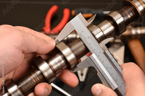 car mechanic measures the size of lobes, cams