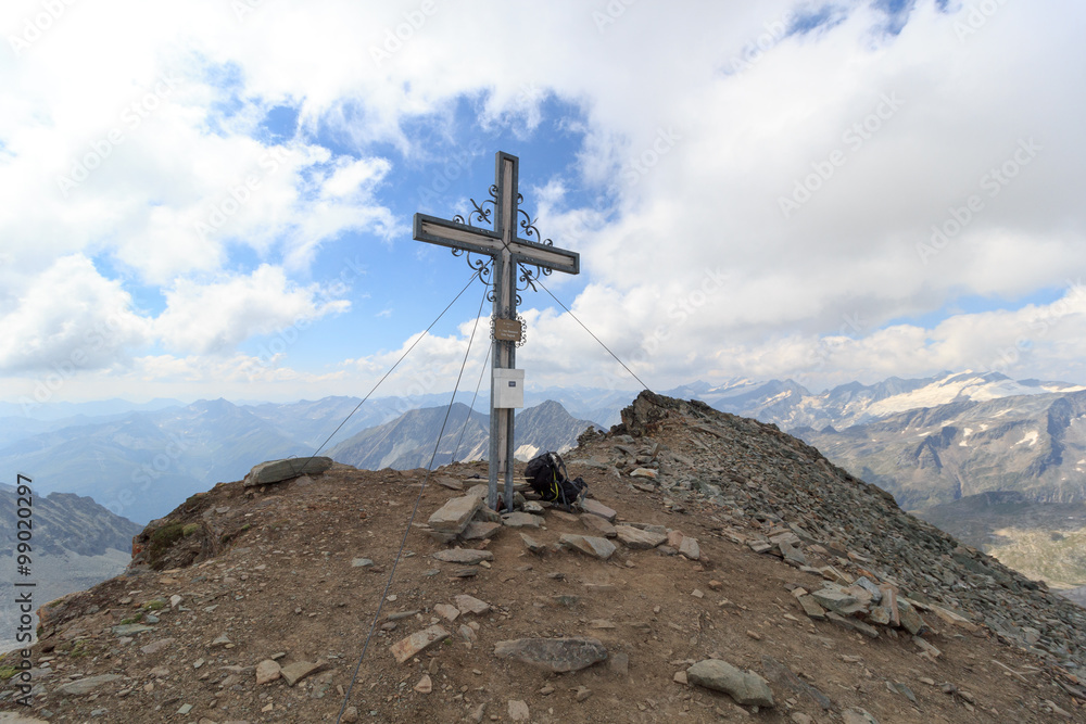 Summit cross and backpack on mountain Weißspitze with panorama in Hohe Tauern Alps, Austria