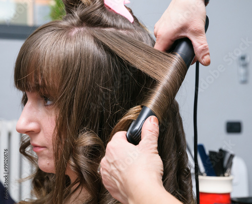 Ragazza dal parrucchiere che arriccia i capelli, fuoco selettivo