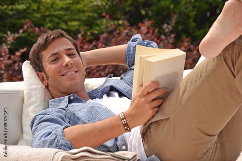Hombre relajado recostado leyendo un libro en la piscina de su casa. photo