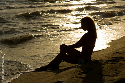 Beautiful, long haired slim young woman at the beach, sunset