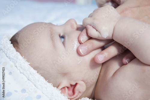 Mother applying cream over baby boy photo