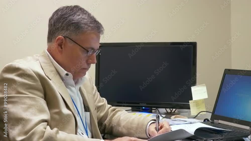 businessman sitting at his office desk going over some papers businessman sitting at his office desk going over some papers