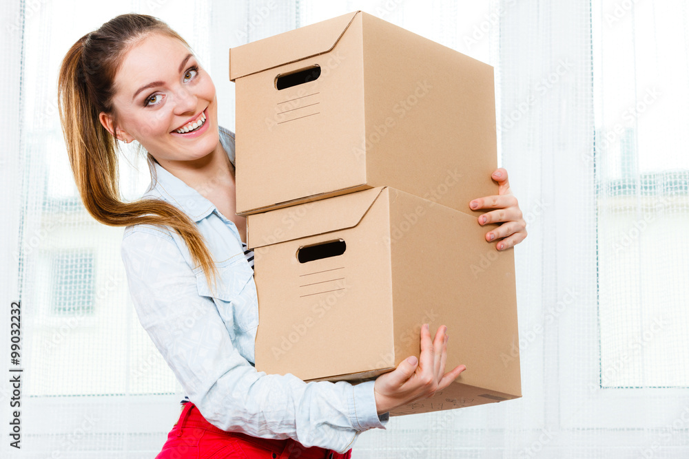 Happy woman moving into house carrying boxes. Happy woman moving into house carrying boxes.