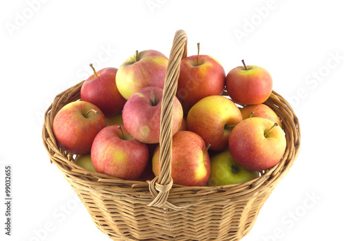Brown wicker basket full of ripe selected apples isolated on white closeup