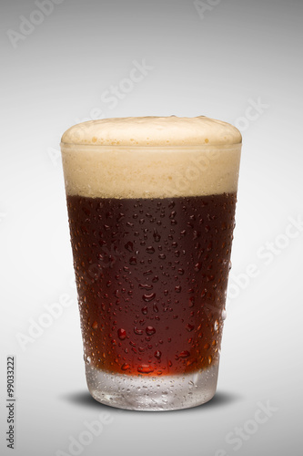 Glass of fresh beer with cap of foam isolated on white backgroun photo