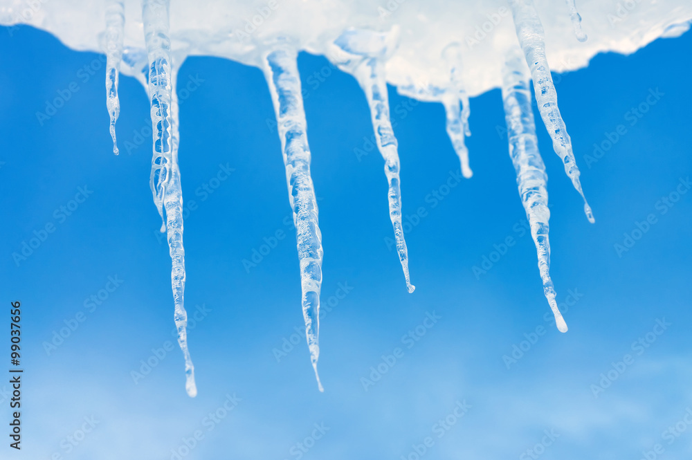 Icicles on background of blue sky with clouds Icicles on background of blue sky with clouds