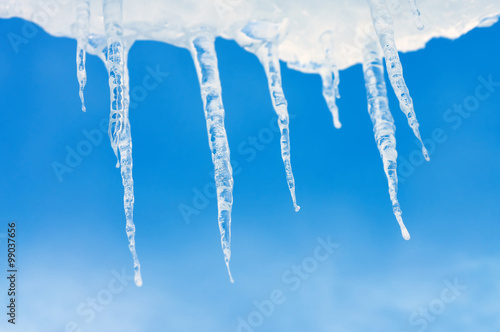 Icicles on background of blue sky with clouds