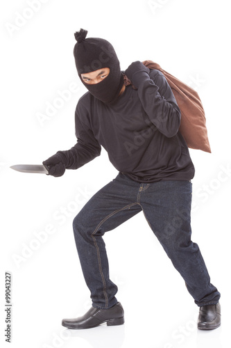 Thief with bag and holding knife on white background  © japhoto