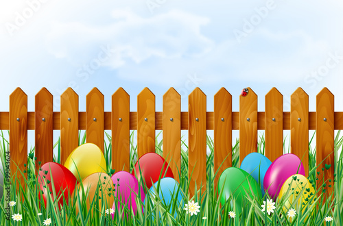 Easter background with easter eggs in grass and wooden fence