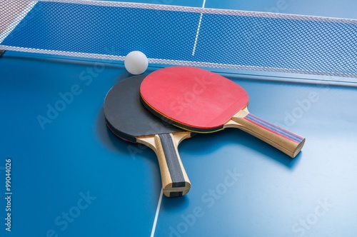 Ping pong rackets with net on blue table.