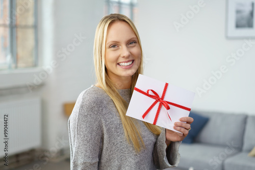 lächelnde frau mit einem geschenk-gutschein in ihrer wohnung photo