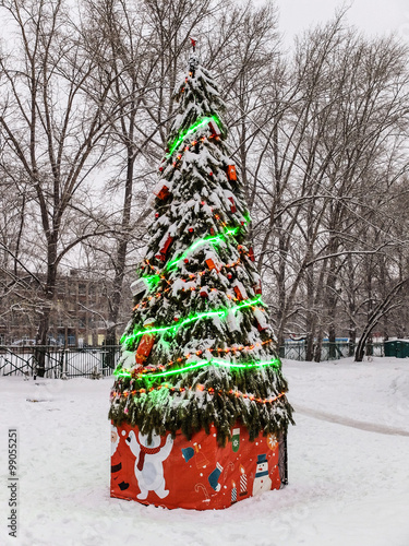 Новогодняя ёлка с горящей гирляндой во дворе photo