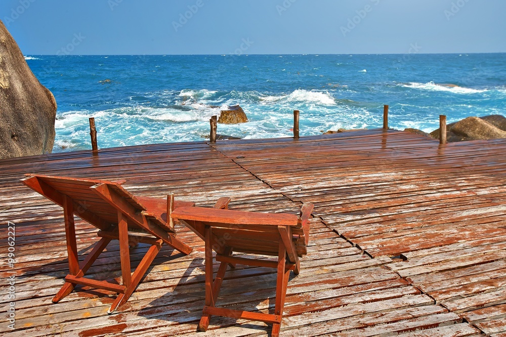 Sun beds on a wooden bridge in the sea 