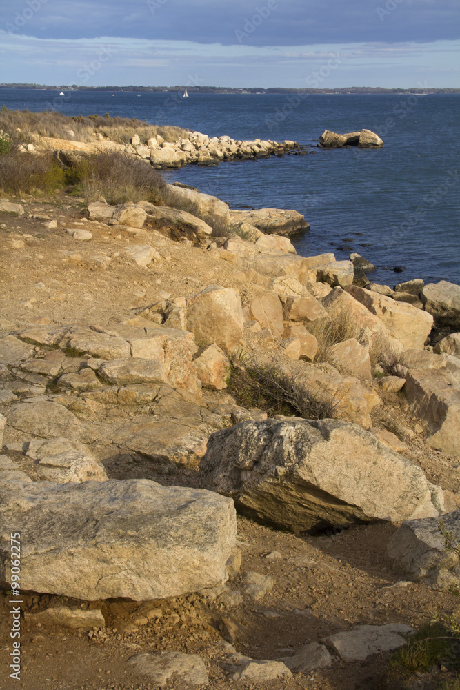 Curving shoreline with boulders and gravel along the Connecticut coast on Long Island Sound.