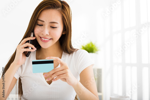 young woman talking on the phone and showing credit card