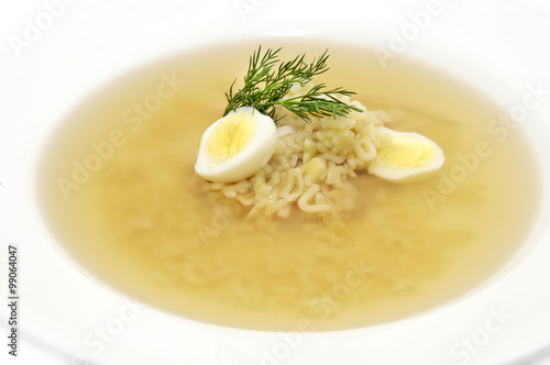 broth with pasta greens and quail egg in a white plate