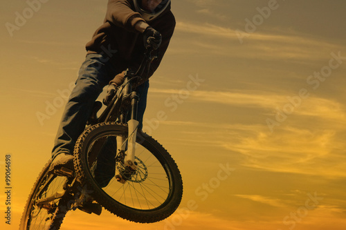 Mounatin bike jump against nice sunrise sky with copyspace photo