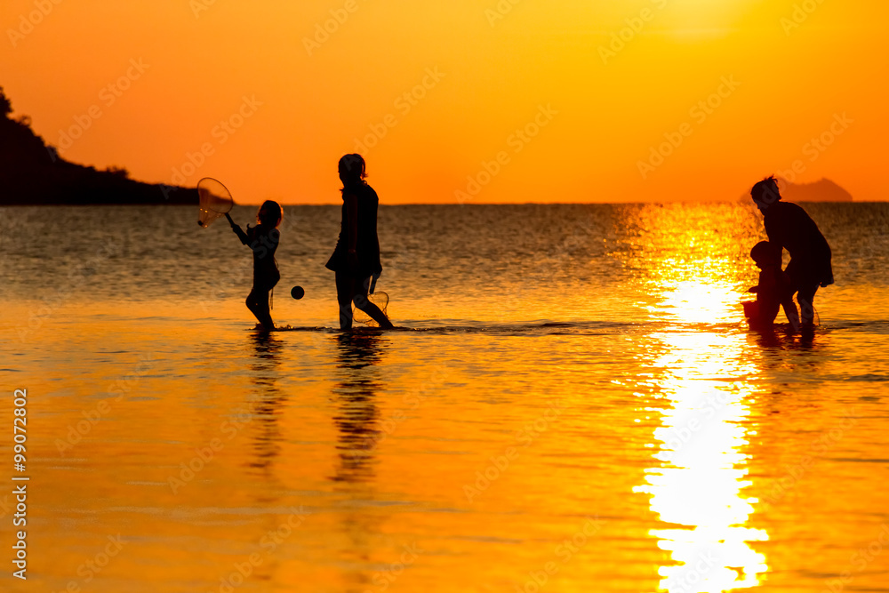 Young mothers and little daughters walking in the sea at the sunset
