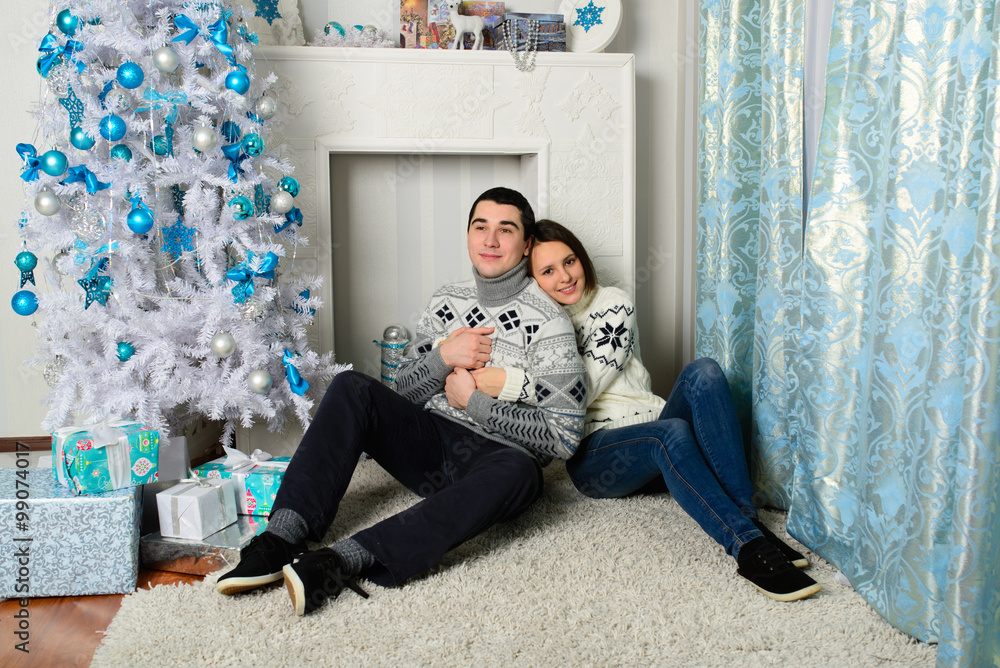 Naklejka premium Nice love couple sitting on carpet in front of fireplace