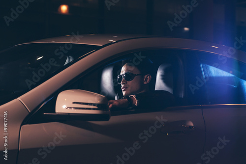 Side view of asian man with sunglasses in car at night.