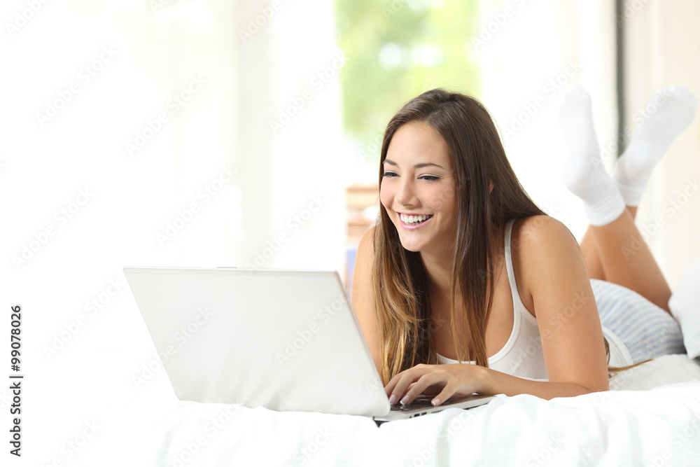Girl browsing in a laptop in the bedroom Girl browsing in a laptop in the bedroom