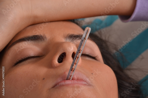 mujer enferma con termometro en la boca.