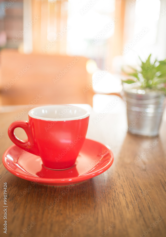 Red cup of coffee and green plant bucket on wooden table Red cup of coffee and green plant bucket on wooden table