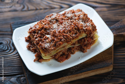 Meat and cheese lasagna, rustic wooden background, studio shot