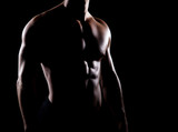 Strong and muscular body of man shaded over black background.