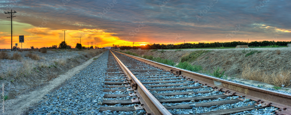 Obraz premium Panoramiczny widok torów kolejowych przekraczających ramę od prawej do lewej.