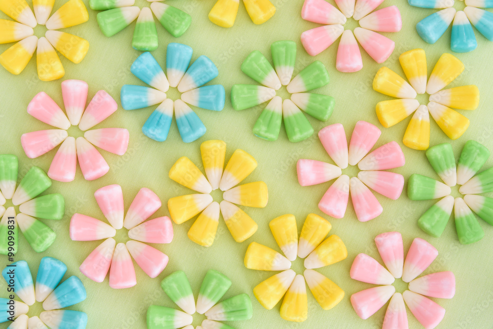 Festive Easter candy corn in flower patterns on a light green background
