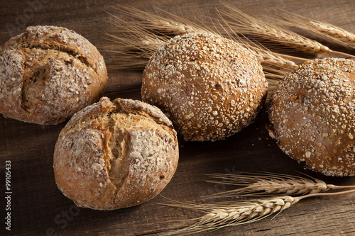 Bread and wheat ears on wooden background