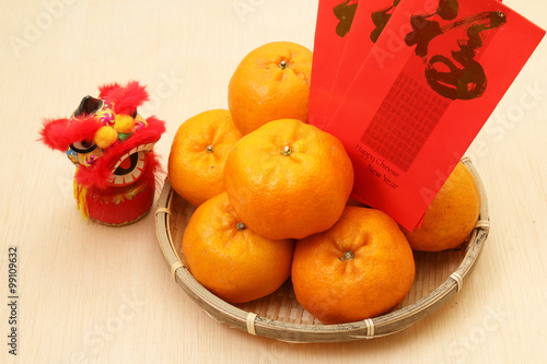 Mandarin oranges in basket with Chinese New year red packets and mini lion doll photo