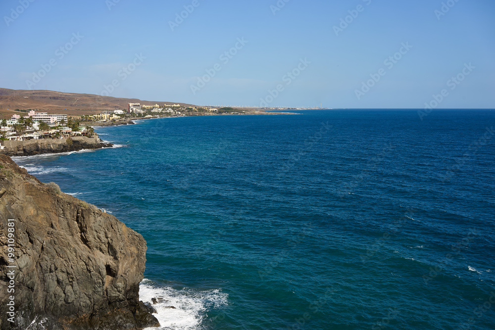 View down the cliffs of Gran Canaria on the wide atlantic ocean / green and blue water under great cliffs of gran canaria