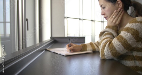 Moving shot of healthy Japanese women writing at office