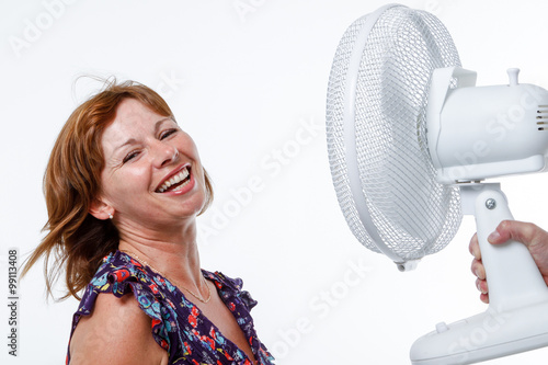 Middle-aged woman cools down with an electric fan