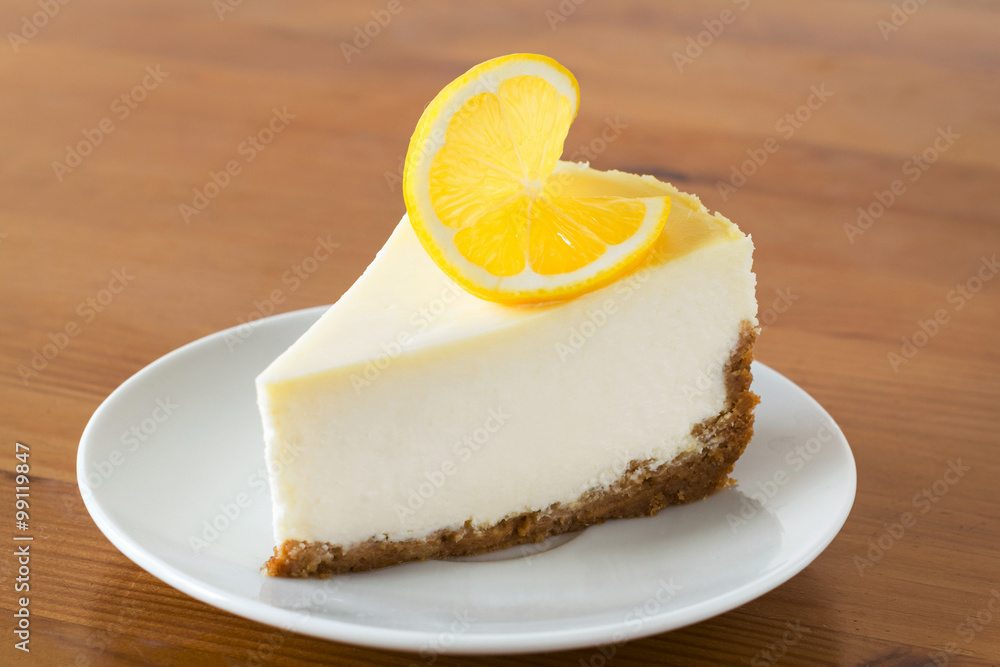Slice of Lemon Cheesecake on white plate on wooden background Slice of Lemon Cheesecake on white plate on wooden background