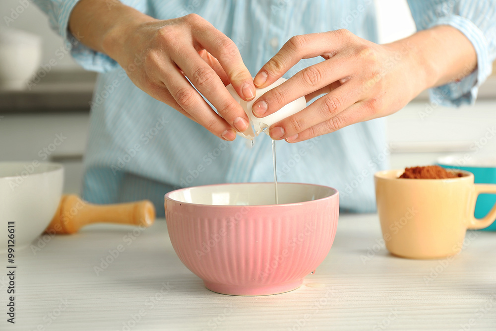 Woman is breaking an egg into a bowl Woman is breaking an egg into a bowl