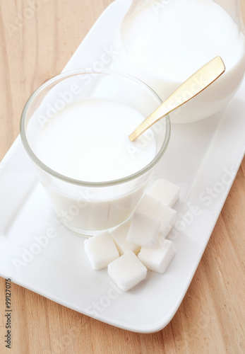 glass of milk with golden spoon and sugar cubes