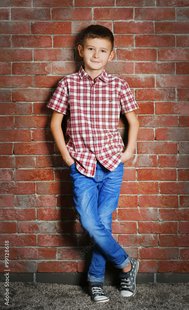 Cute little boy on brick wall background. Kids fashion concept Cute little boy on brick wall background. Kids fashion concept