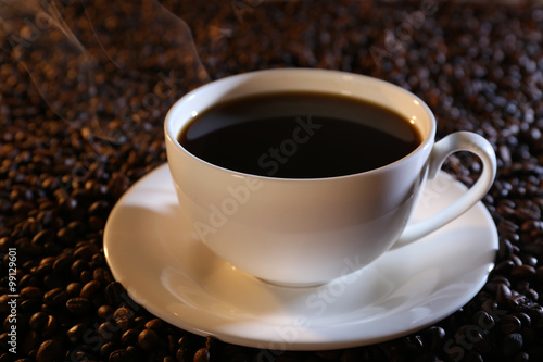 Cup of hot coffee on coffee beans background