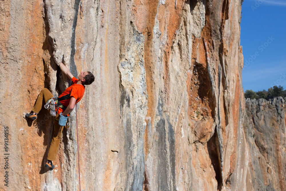 Fototapeta premium Young male climber hanging by a cliff.