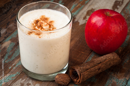 Apple crumble smoothie milkshake topped with cinnamon and nutmeg spices. Served on a rustic wooden table. photo