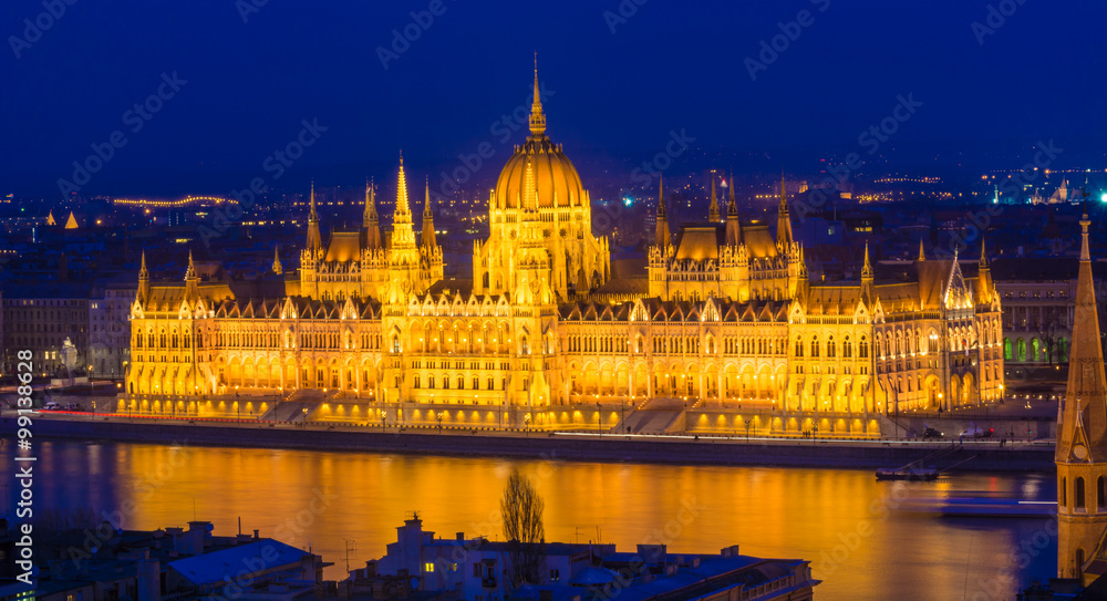 Budapest Parliament building illuminated at dusk reflected in Danube river in Hungary